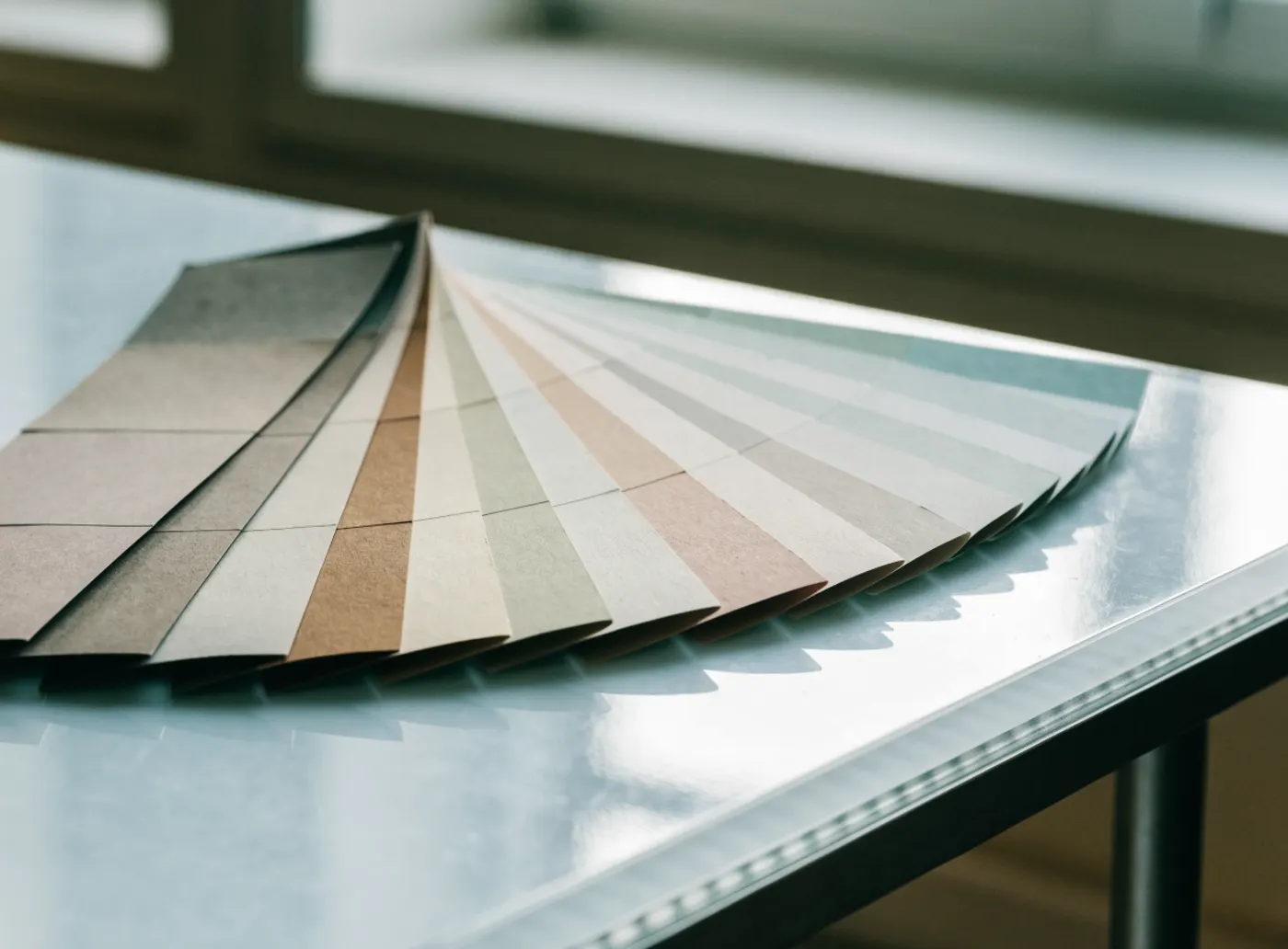 Nuancier de couleurs déplié sur une table claire, un échantillon avancé par rapport aux autres