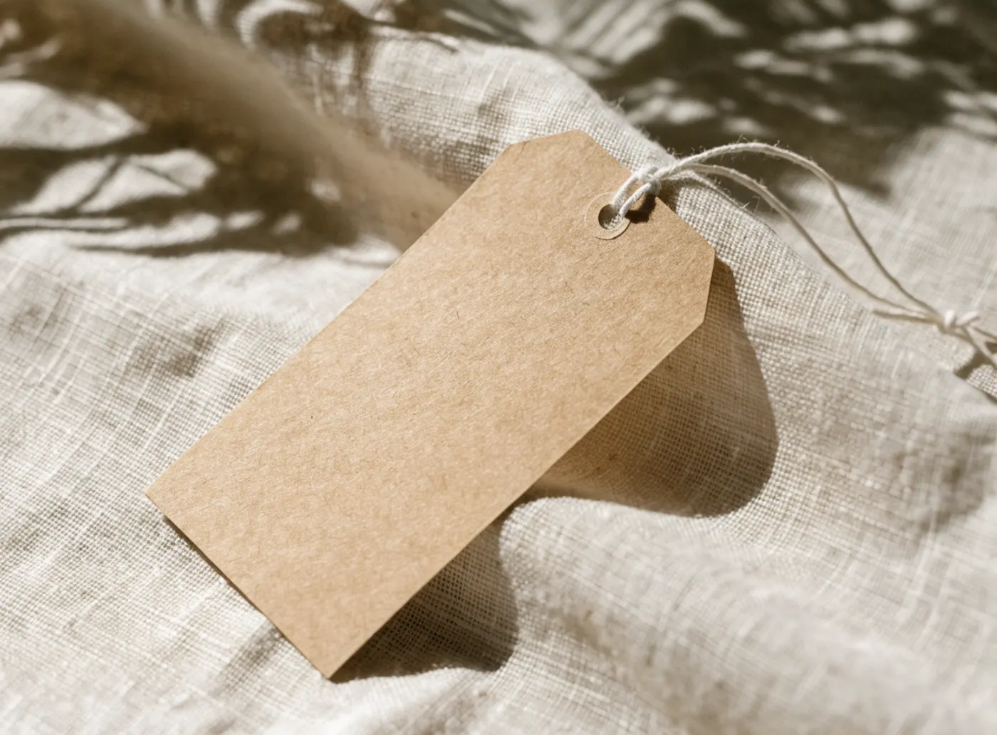 Étiquette de papier kraft vierge attachée avec une ficelle, sur du lin clair