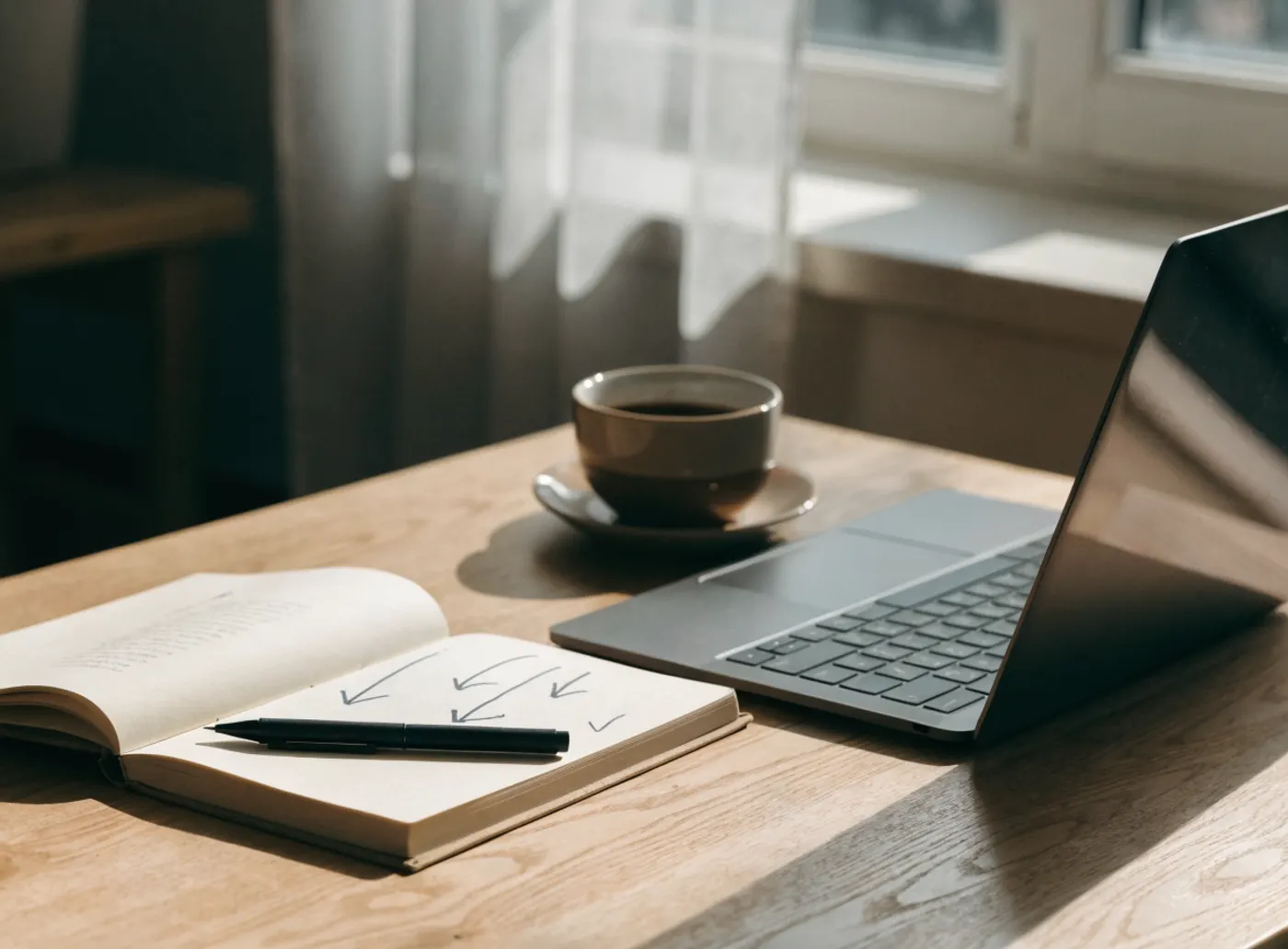 Carnet ouvert avec des flèches dessinées à la main, à côté d’un portable et d’un café