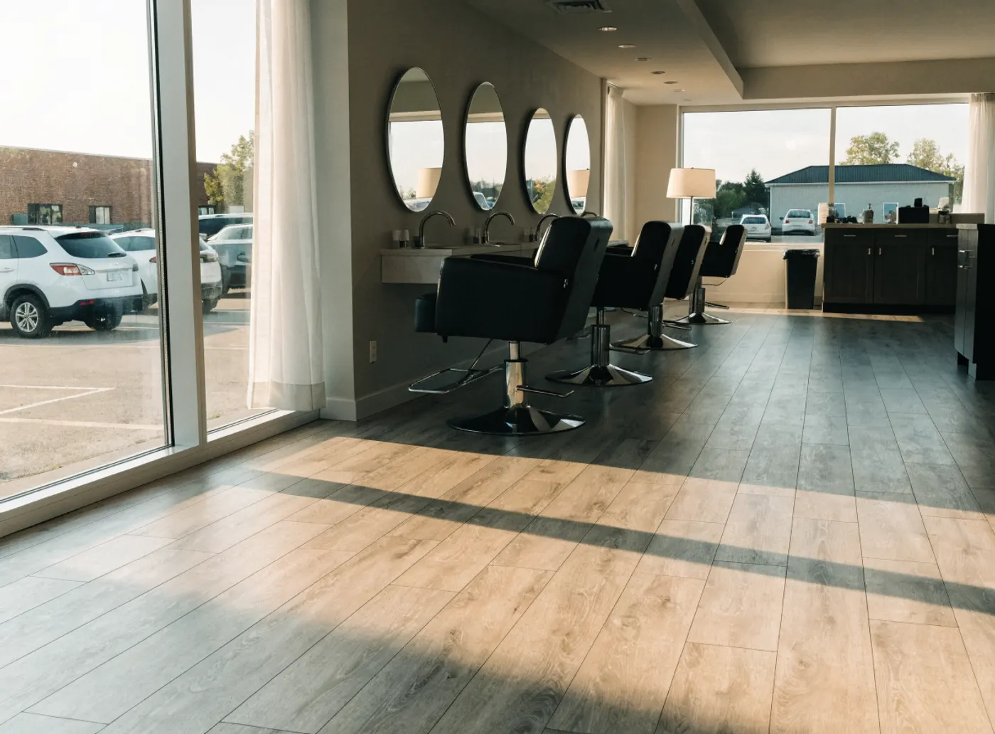 Salon de beauté vide le matin, fauteuils et miroirs ronds, stationnement de boulevard par la fenêtre