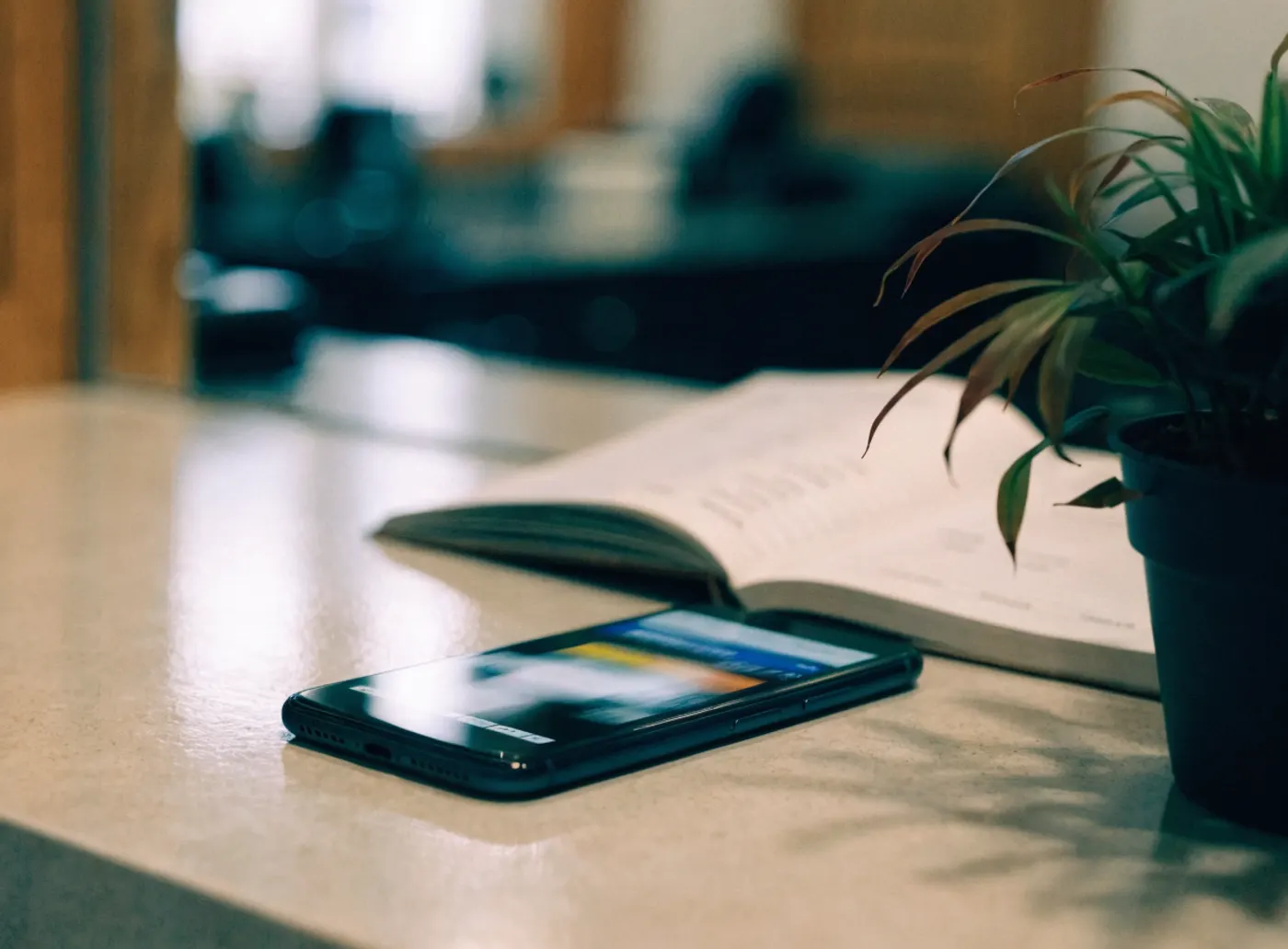 Téléphone posé sur le comptoir d’accueil d’un salon, à côté d’un livre ouvert et d’une plante